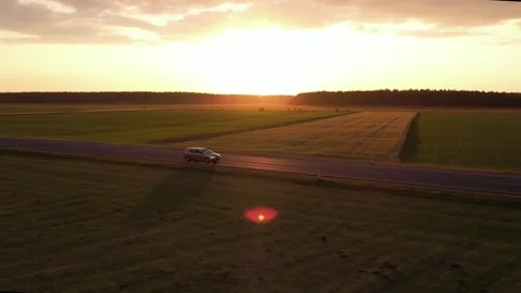 Cars driving on the road between the fields	 in sunset Stockbeeldmateriaal 243512078