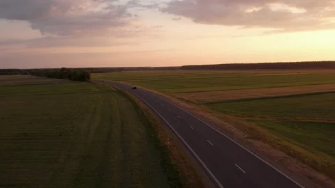 Cars driving on the road between the fields	 in sunset Stockbeeldmateriaal 243512082