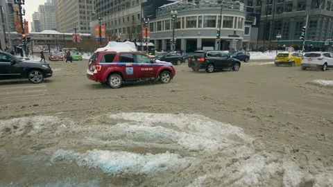 Cars driving in snow filled intersection in Chicago Stock Footage 87344623