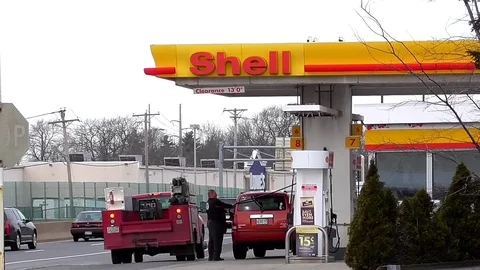 Cars fuel up at local Shell gas service station, highway traffic Stock Footage