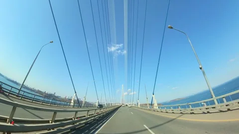 Cars Navigating a Modern Cable-Stayed Bridge Under a Clear Blue Sky. Cars Drive Stock Footage 314699591