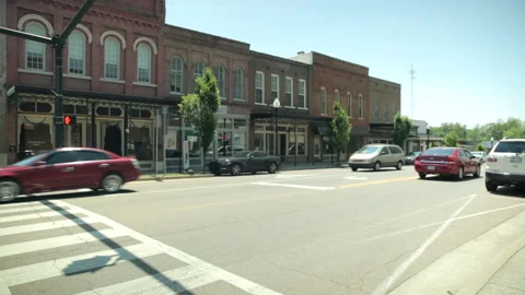 Cars pass down small town main street Stock Footage 236708045