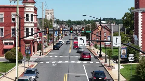 Cars queue at red light beneath left turn only sign on busy main street, red Stock Footage 343011252