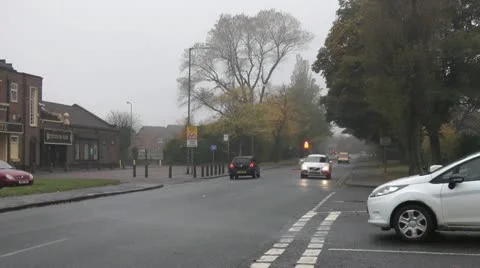Cars turn at junction of tree lined road on misty autumn day Stock Footage 14815445