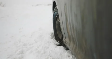 Car's wheels spin in place while trying to drive along snowy street. Vehicle Stock Footage 194697224