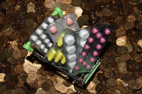 A cart with blisters of tablets on the background of defocus coins Stock Photos