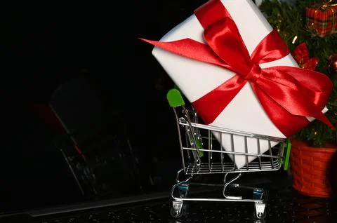 Cart on a computer board with a huge gift beside christmas tree. Online sho.. Stock Photos