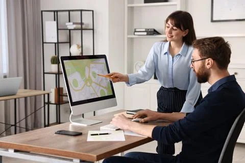 Cartographers working with cadastral map on computer at table in office Fotos de archivo