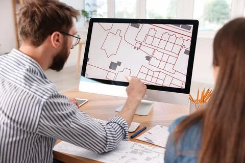 Cartographers working with cadastral map on computer at table in office, ba.. Fotos de archivo