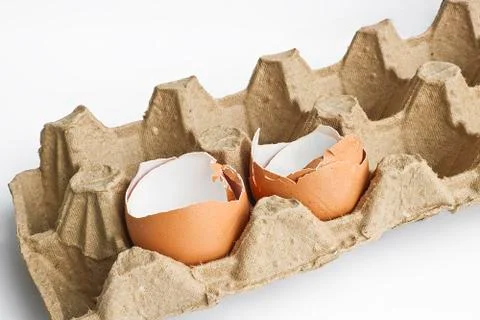 Carton packaging for eggs with broken eggshell on a light background. Stock Photos