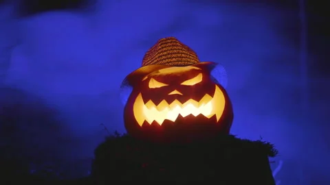 Carved face in a pumpkin against the background of forest on a stump. Stock Footage 162547399