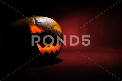 The Carved Face Of Pumpkin Glowing On Halloween On Red Background