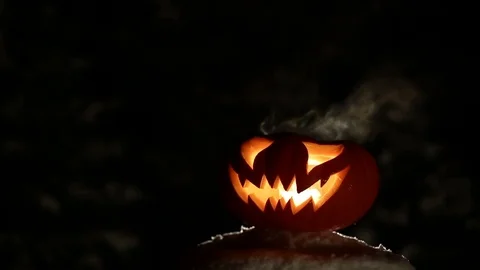 Carved Halloween pumpkin lights inside with flame on a black background close up Stock Footage 80319070