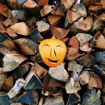 A carved happy face pumpkin on a stack of logs 스톡 사진