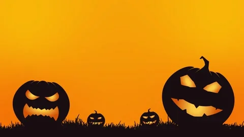 Carved jack-o-lantern pumpkins glowing on grass against an orange background Stock Footage 346068152