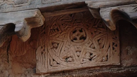 Carved mud brick panel with geometric pattern under wooden eave 動画素材 347973200
