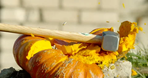 A carved orange pumpkin gets smashed with a giant hammer Stock Footage 145054204