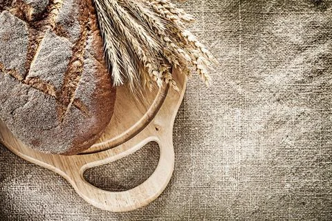 Carving board bread bundle of wheat ears on burlap background 写真素材