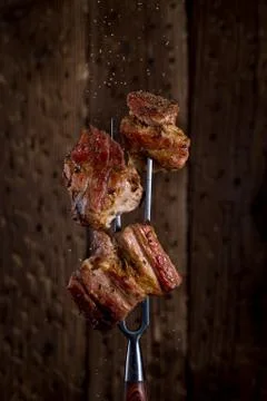 Carving fork with pieces of steak on rustic background Stock Photos