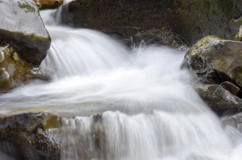 Cascade falls over mossy rocks Stock Photos