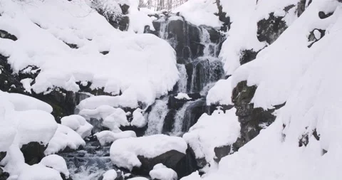 Cascade of mountain waterfall in snow winter morning. River water flowing Stock Footage 233770082