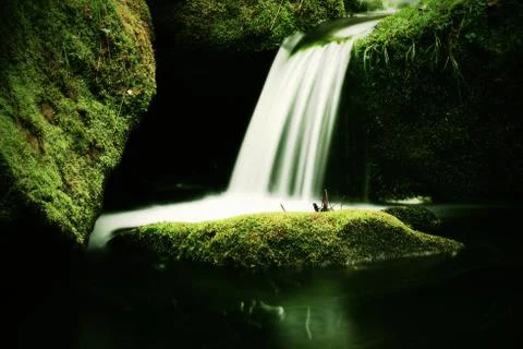 Cascade on small mountain stream. Cold crystal  water is falling over mossy b Stock Photos