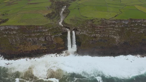 Cascade streams from steep cliff into the ocean. River ends with waterfall Stockbeeldmateriaal 117770324
