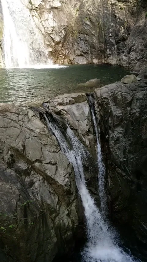 Cascade of two waterfalls with rocks among trees. Vertical. Stock Footage 151068892
