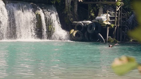 Cascade waterfall splashing in tropical waterfall and young woman swimming in Stock Footage 101401565