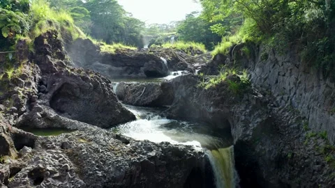 Cascading river waterfalls cutting through rugged volcanic rock and rainforest Stock Footage 315274265