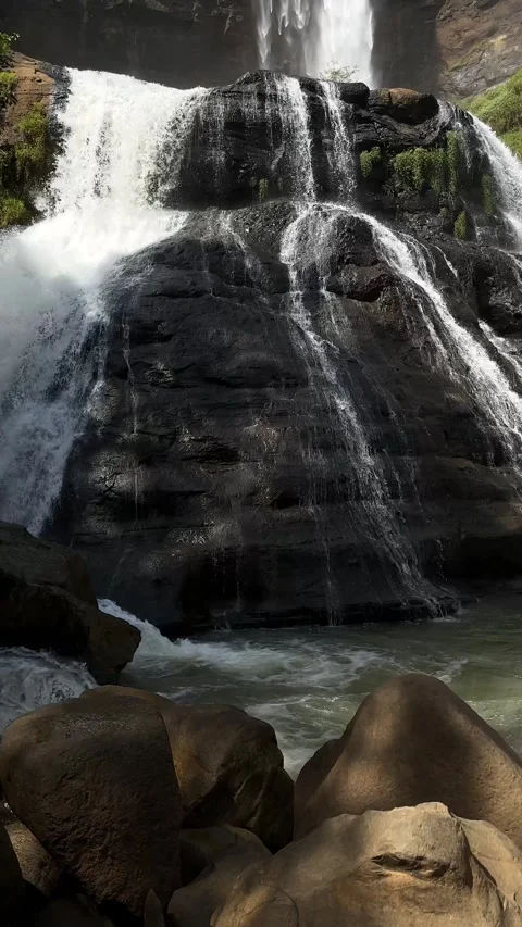 Cascading Tiered Waterfall Over Dark Rocks in Lush Green Forest, Vertical Stock Footage 325646192