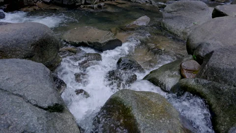 Cascading water flowing over large, smooth rocks at Phlio Waterfall Video stock 295785975
