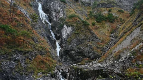 A cascading waterfall in autumn setting with orange grass Stock Footage 260847461