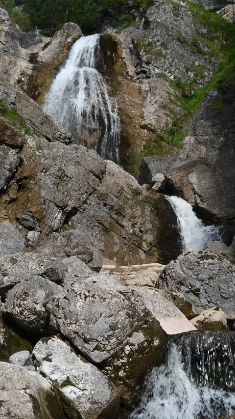 Cascading waterfall between rocks in the mountains, vertical shot Stock Footage 260870797