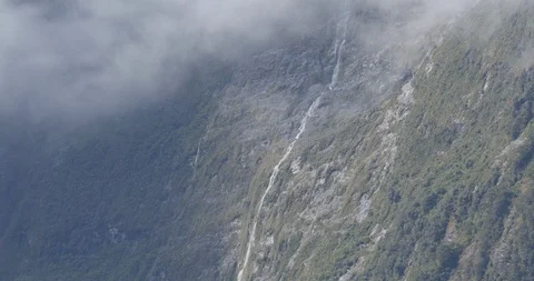 A cascading waterfall cuts a line through the cliffs of Milford Sound Stock Footage 120491515