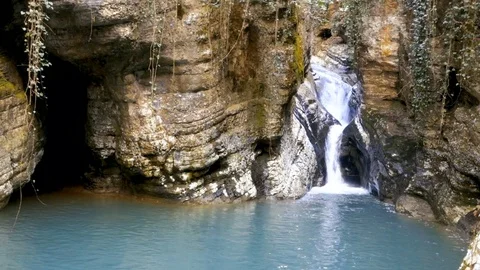 Cascading waterfall falls into  lake between  rocks Stock-Footage 85120175