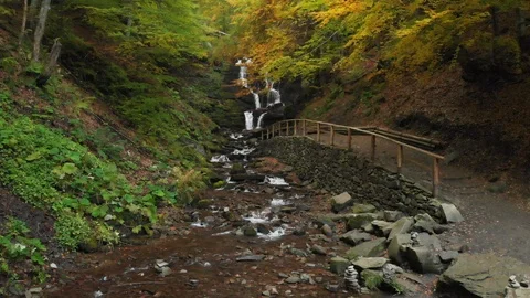 Cascading Waterfall in the Forest. Path and Wooden Railing Stock Footage 105479667