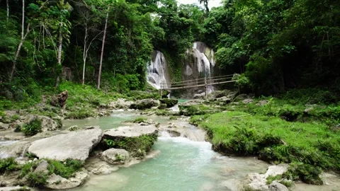 Cascading waterfall surrounded with lush green jungle forest with wooden bridge Stock Footage 271319702