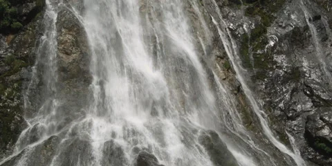 A cascading waterfall throws a veil over dark rock Stock Footage 59528405
