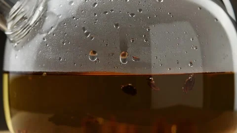 Cascara coffee cherry husks drift in amber infusion under condensation on glass Stock Footage 346585847