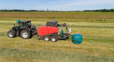 Case tractor with a red straw fixed chamber press during the straw harvest Stock Photos