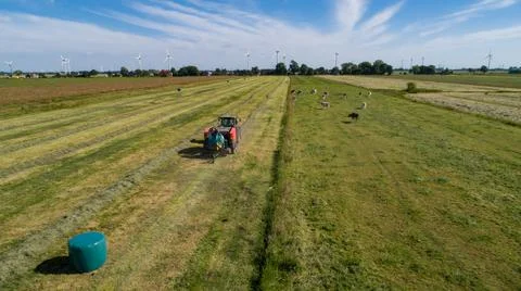 Case tractor with a red straw fixed chamber press during the straw harvest Stock Photos