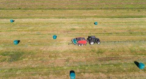 Case tractor with a red straw fixed chamber press during the straw harvest Stock Photos