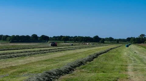 Case tractor with a red straw fixed chamber press during the straw harvest Stock Photos