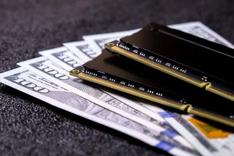 Cash and computer memory modules sit on a black surface during a business Stock Photos