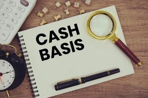 Cash Basis text written on notepad with pen, alarm clock, magnifying glass .. Stock Photos
