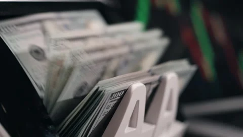 Cash counting machine processes stacks of hundred-dollar bills, displaying the Stock Footage 331079628