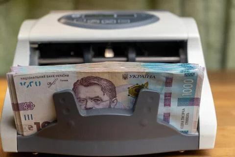 Cash counting machine processing stack of national Ukrainian money bills 스톡 사진
