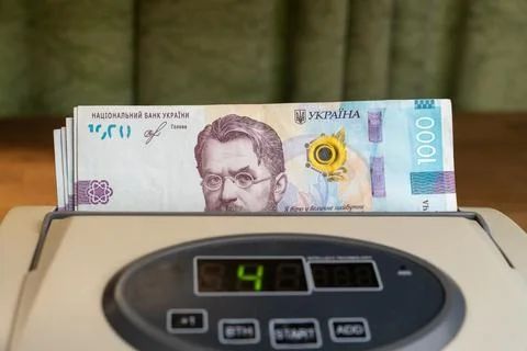 Cash counting machine processing stack of national Ukrainian money bills Stock Photos