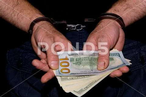 Cash money in the hands of which handcuffed. Stock Photos